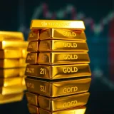 Close-up of shiny gold bars stacked on a reflective surface highlighting the 21-karat purity